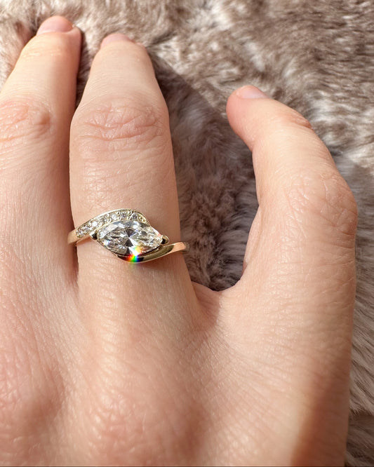 Hand wearing a ring with a large diamond on a fur background