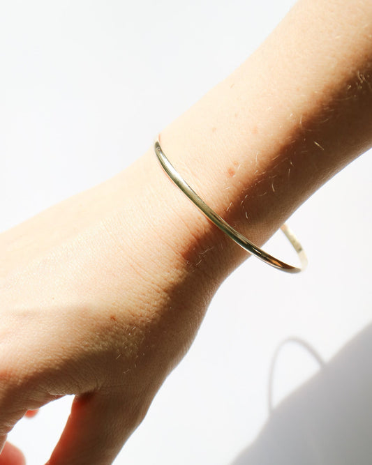 Gold bracelet on a wrist with a white background
