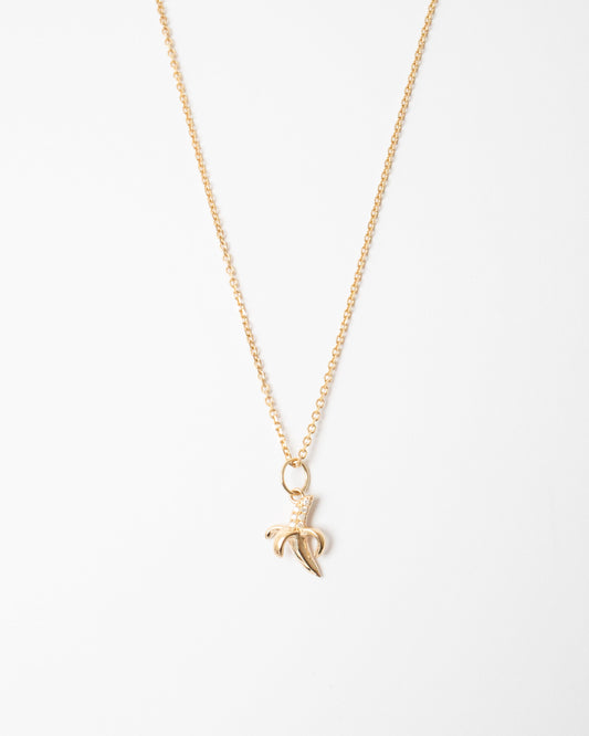 Gold necklace with a banana leaf pendant on a white background