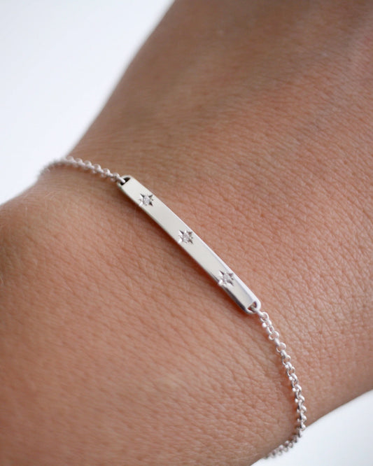 Silver bracelet with star charms on a wrist against a white background