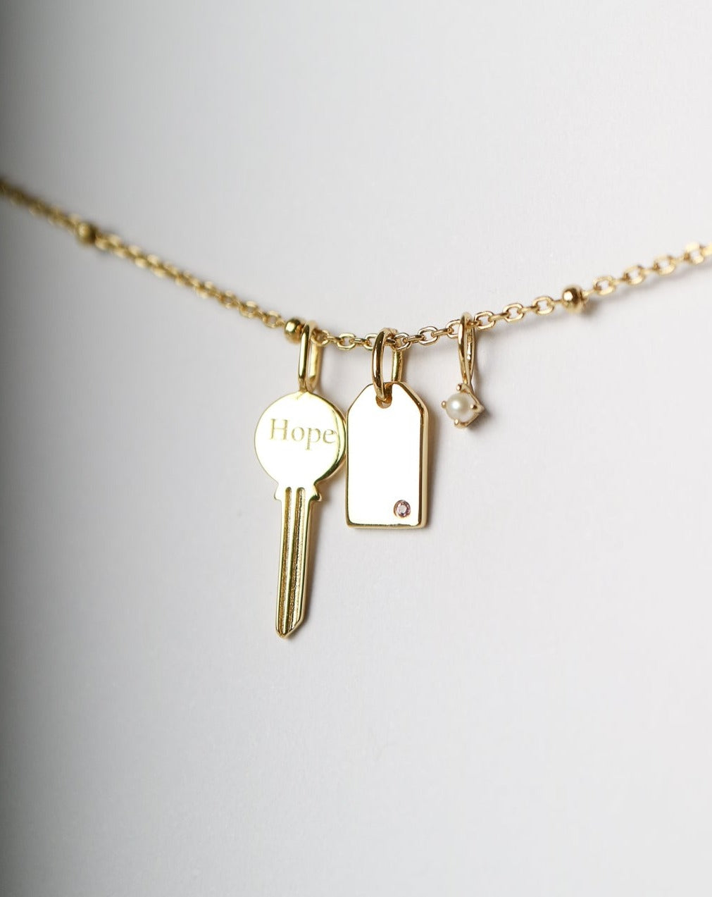 Gold Charm Necklace with key, pearl, gemstone tag