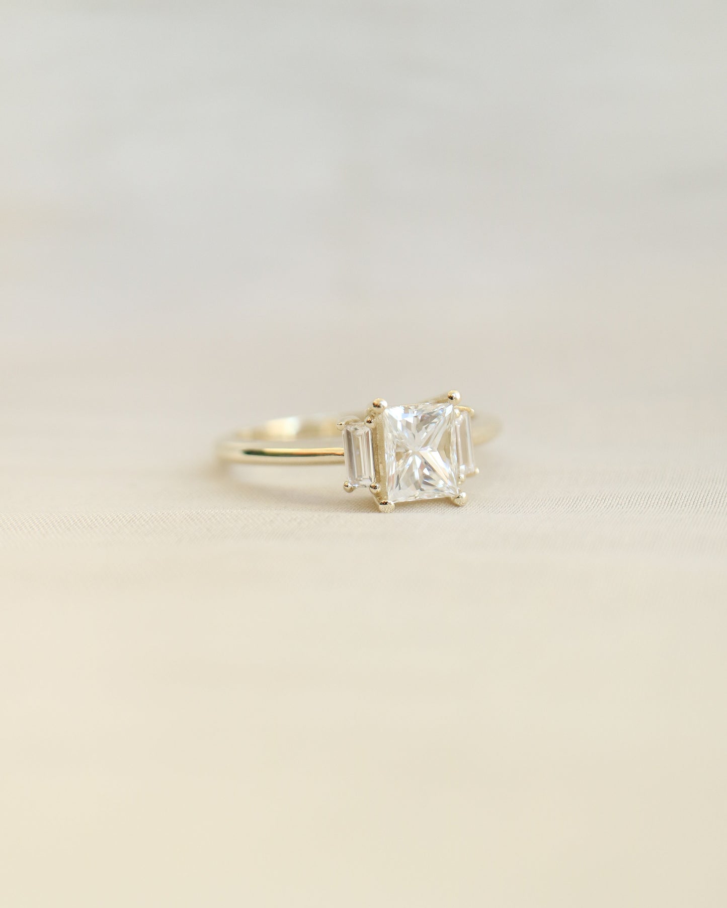 Gold ring with a diamond on a beige background