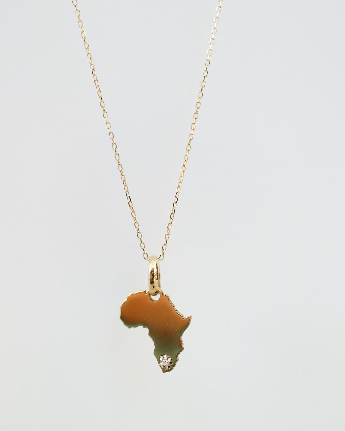 9ct Gold necklace with an Africa-shaped pendant with natural diamond on a light gray background