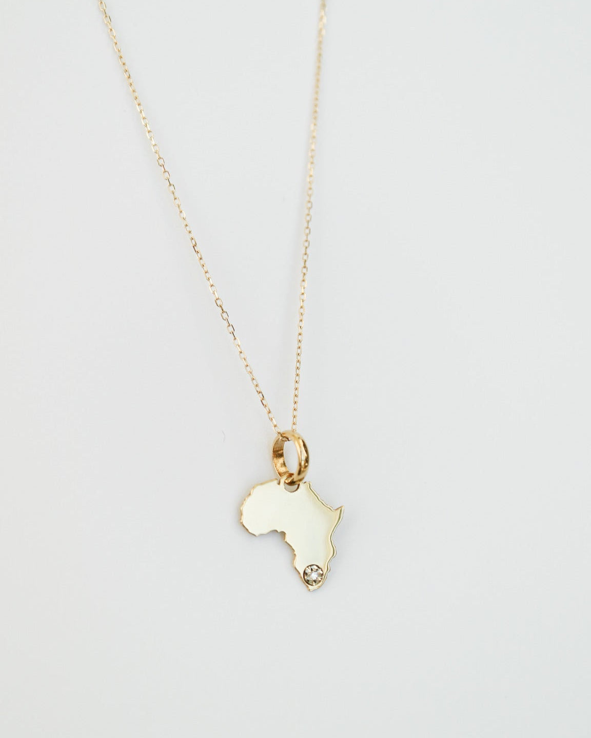 9ct Gold necklace with an Africa-shaped pendant with natural diamond on a light gray background