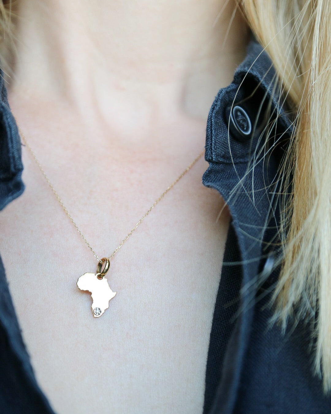 Necklace with a heart-shaped pendant worn by a person with blonde hair.
