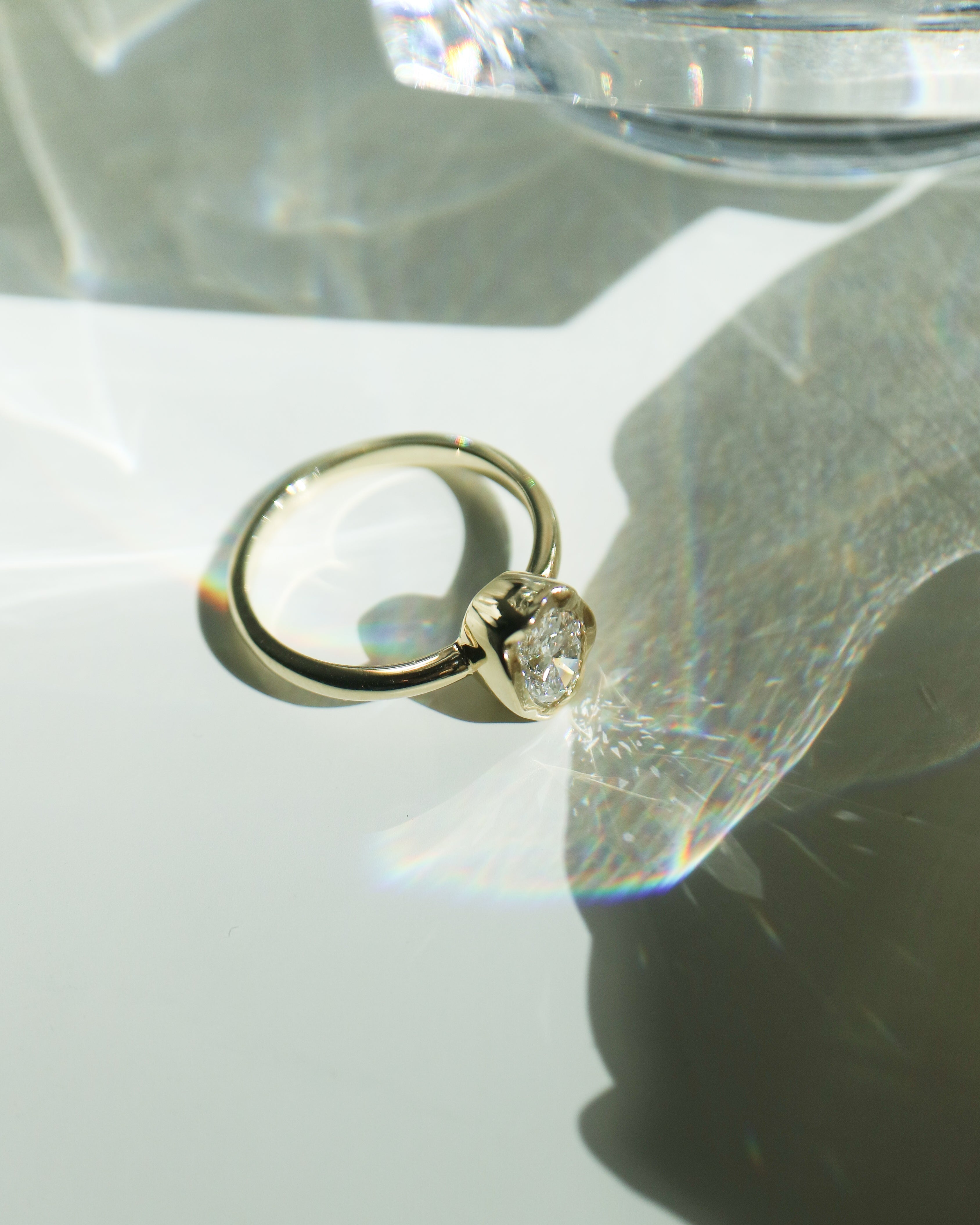 Gold ring with a diamond on a reflective surface