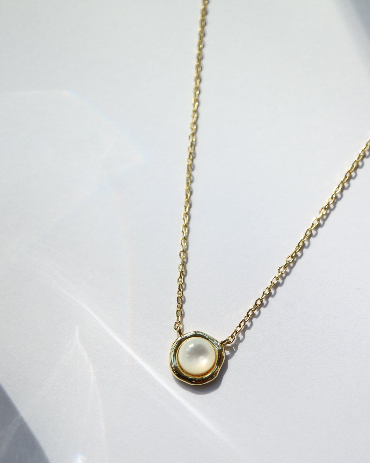 Gold necklace with a round pendant on a white background