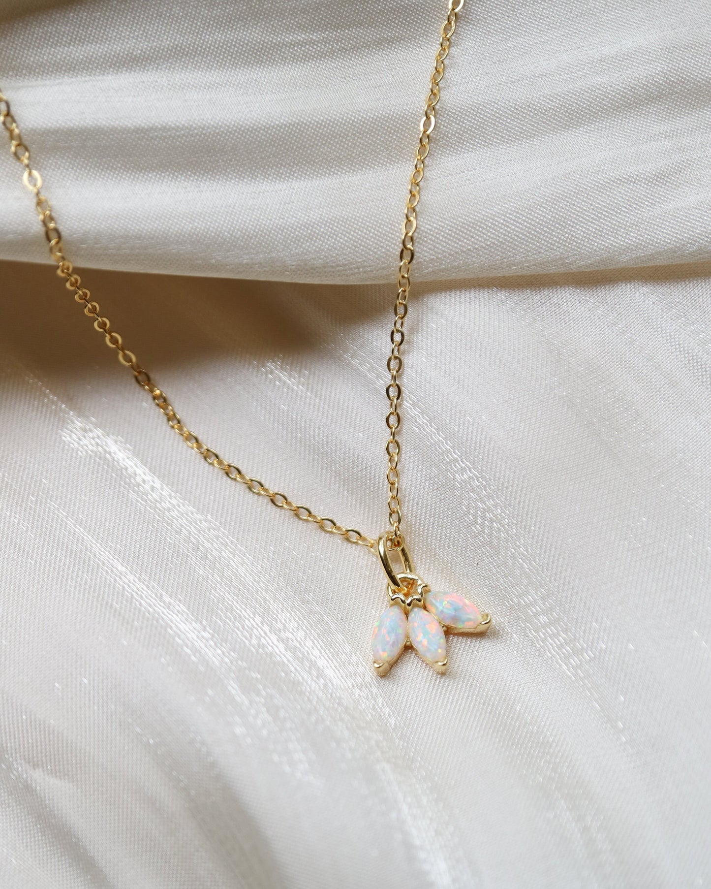 Gold necklace with a small pendant on a white fabric background