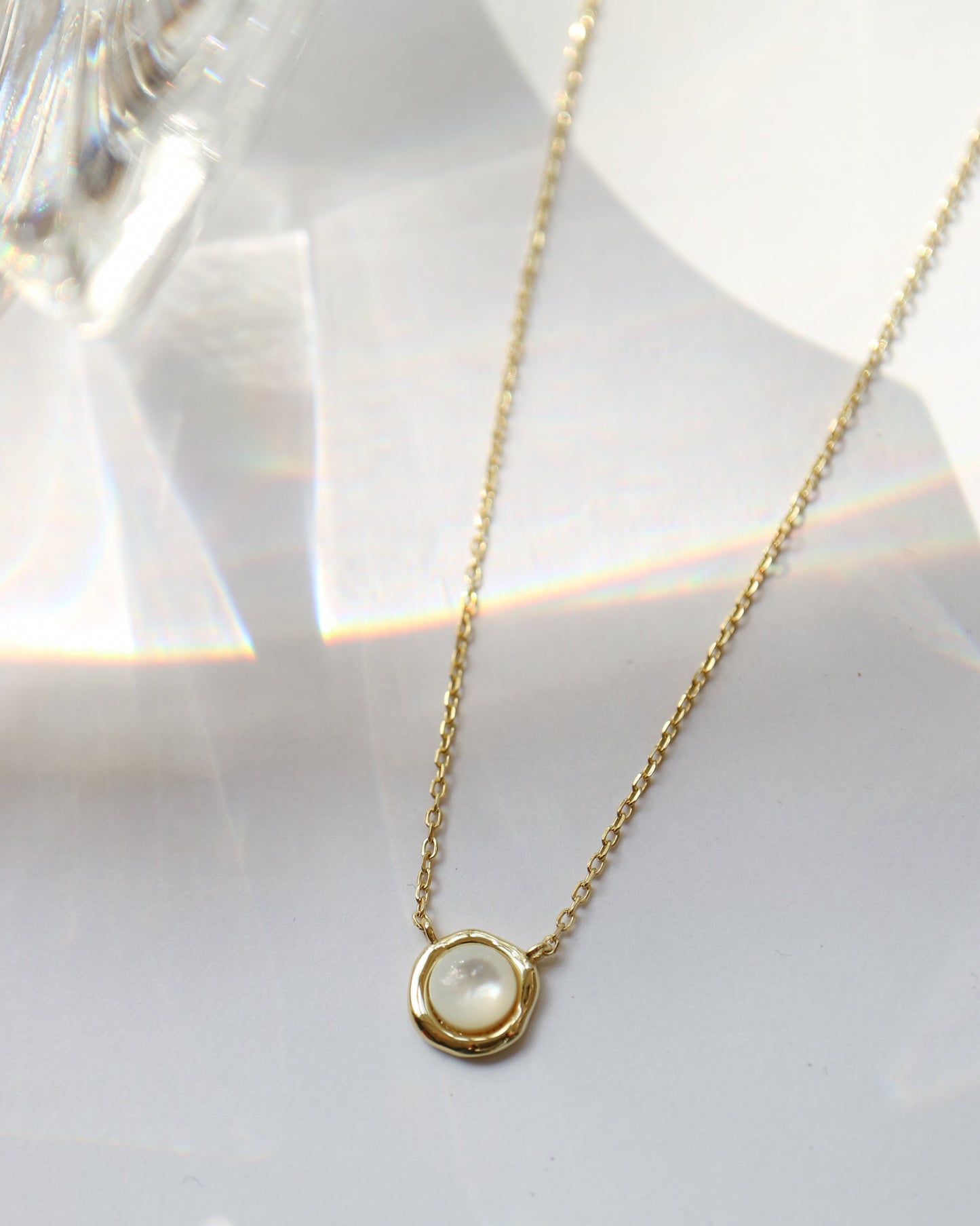 Gold necklace with a round pendant on a white background
