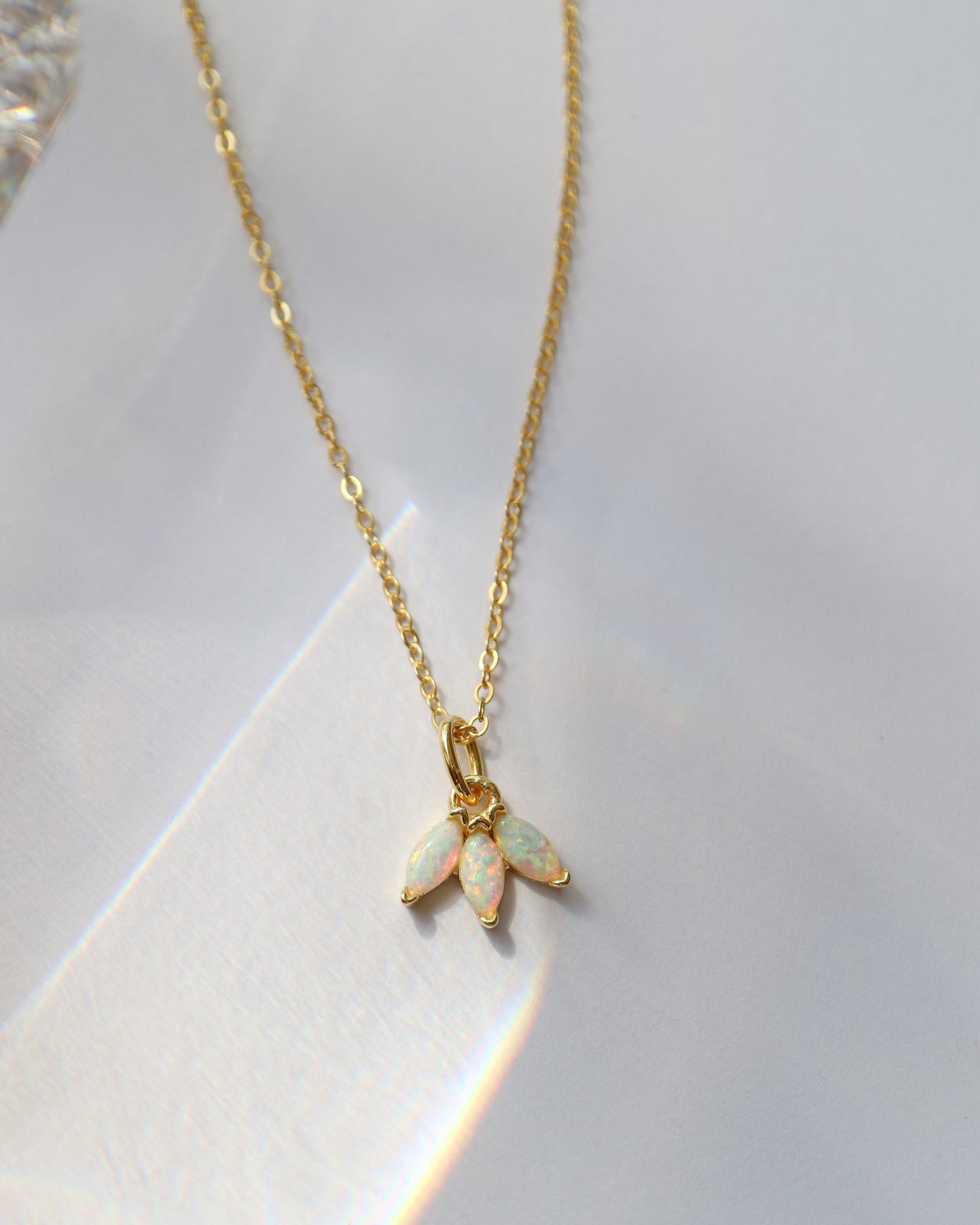 Gold necklace with an opal pendant on a white background