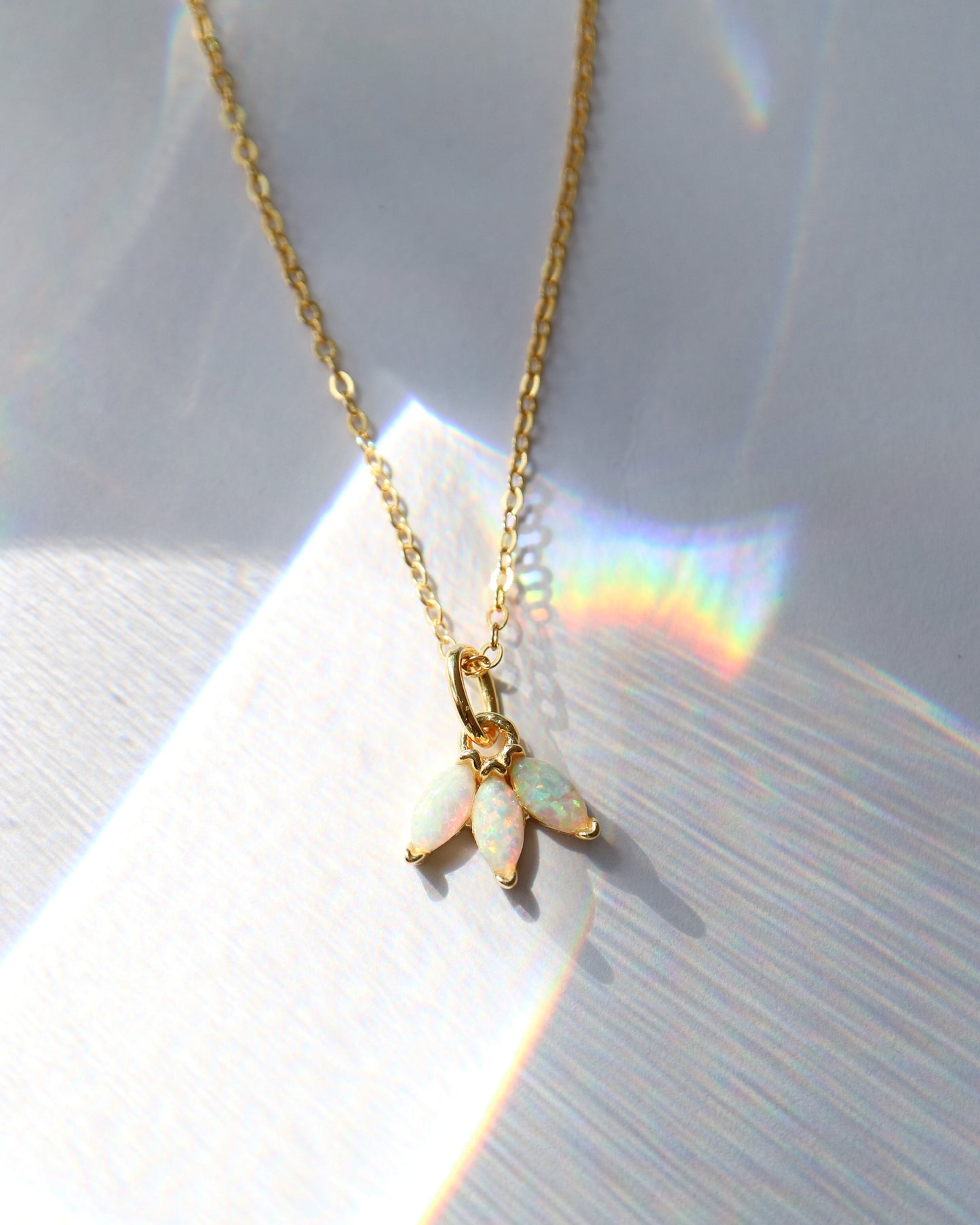 Gold necklace with a leaf-shaped pendant on a light background