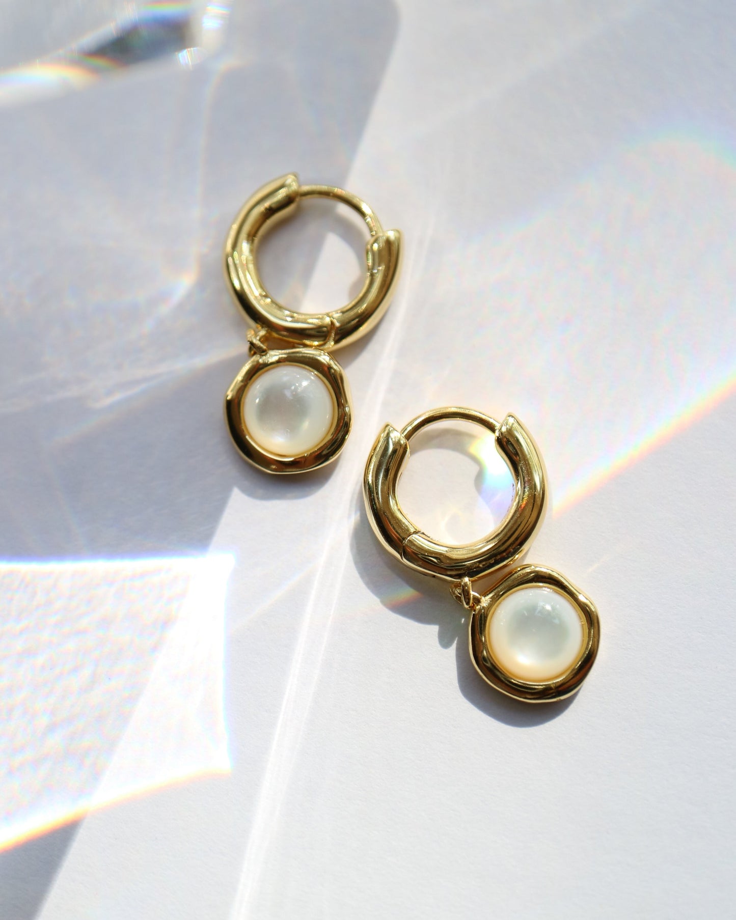 Gold hoop earrings with a central gemstone on a white background