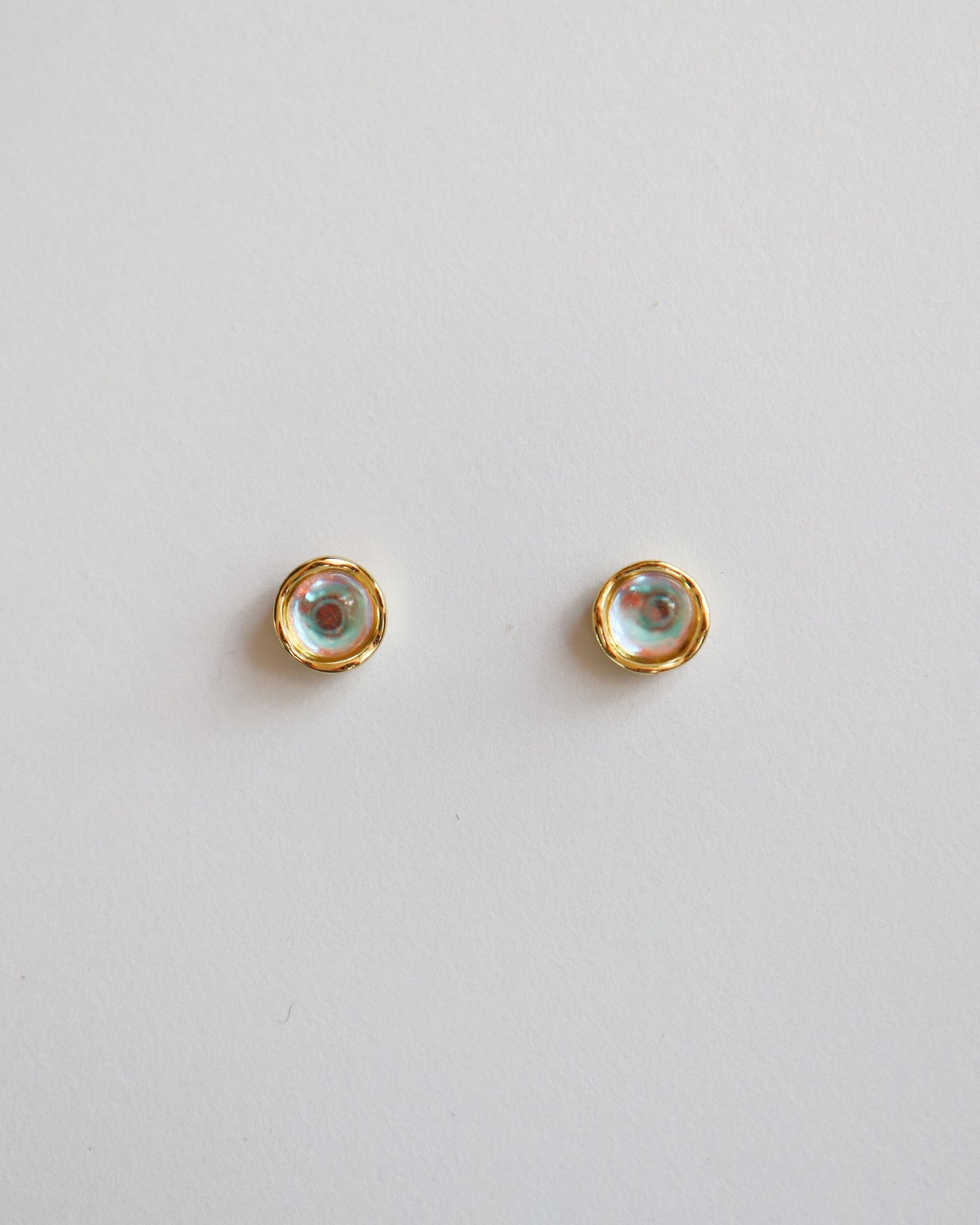 Pair of gold stud earrings on a light gray background