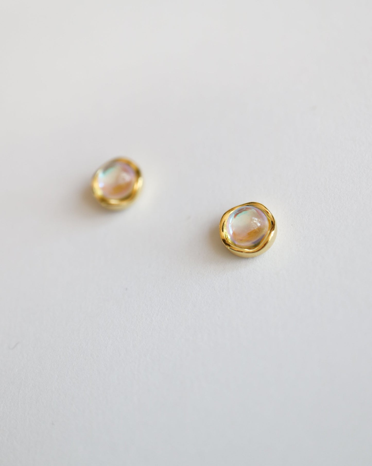 Pair of gold earrings with moonstone gemstones on a light gray background