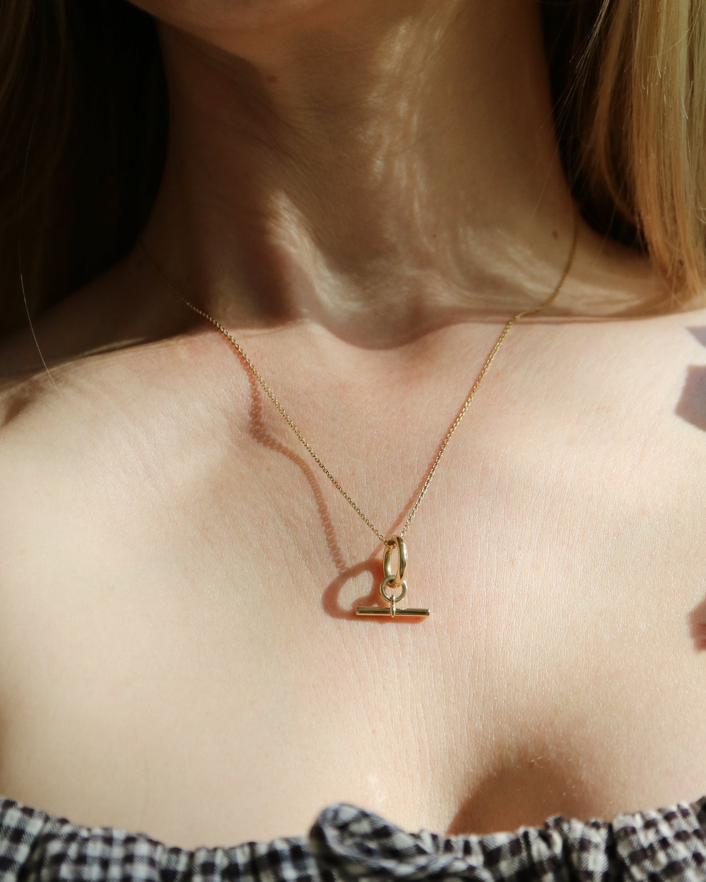 Close-up of a person wearing a gold necklace with a heart-shaped pendant.