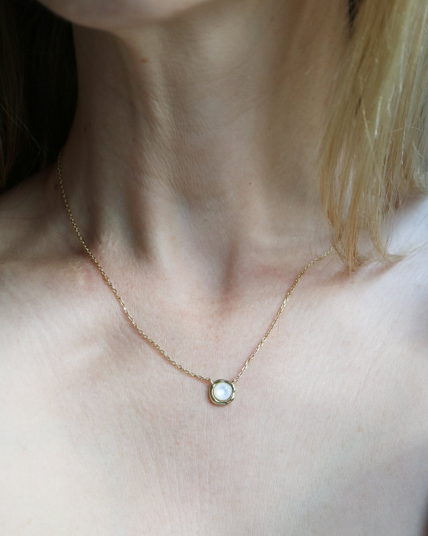 Necklace with a pendant worn by a person in a checkered top