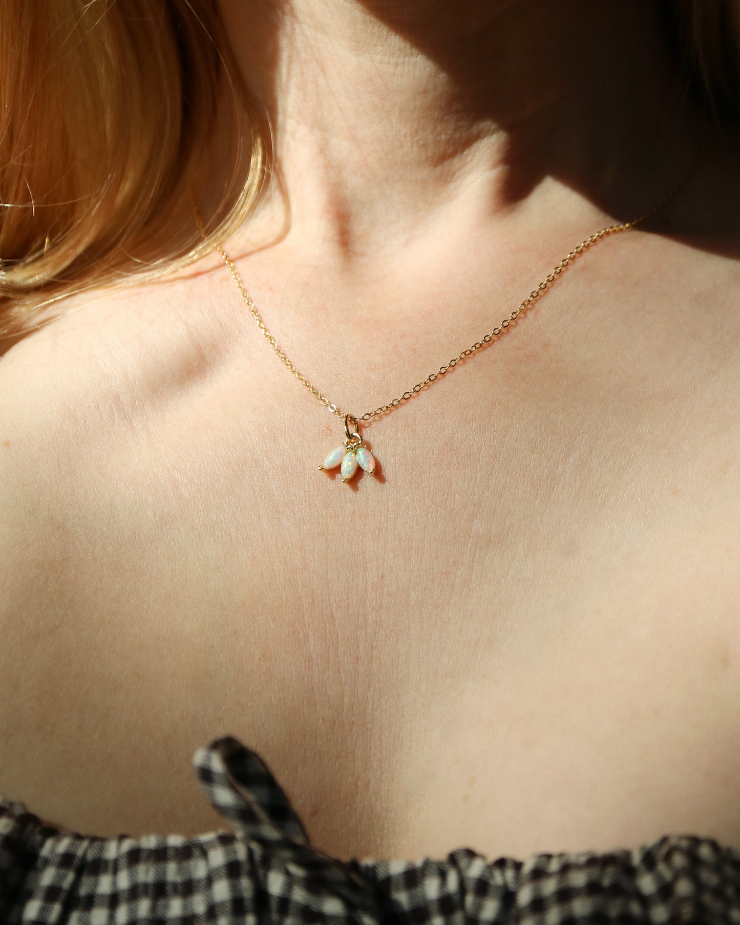 Close-up of a necklace with a pendant on a person wearing a black and white checkered top.