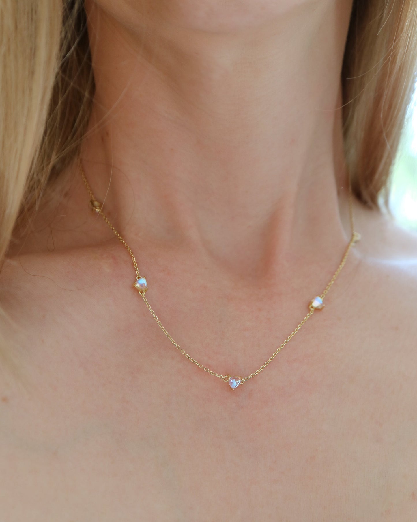 Gold necklace with small beads on a person wearing a checkered top.