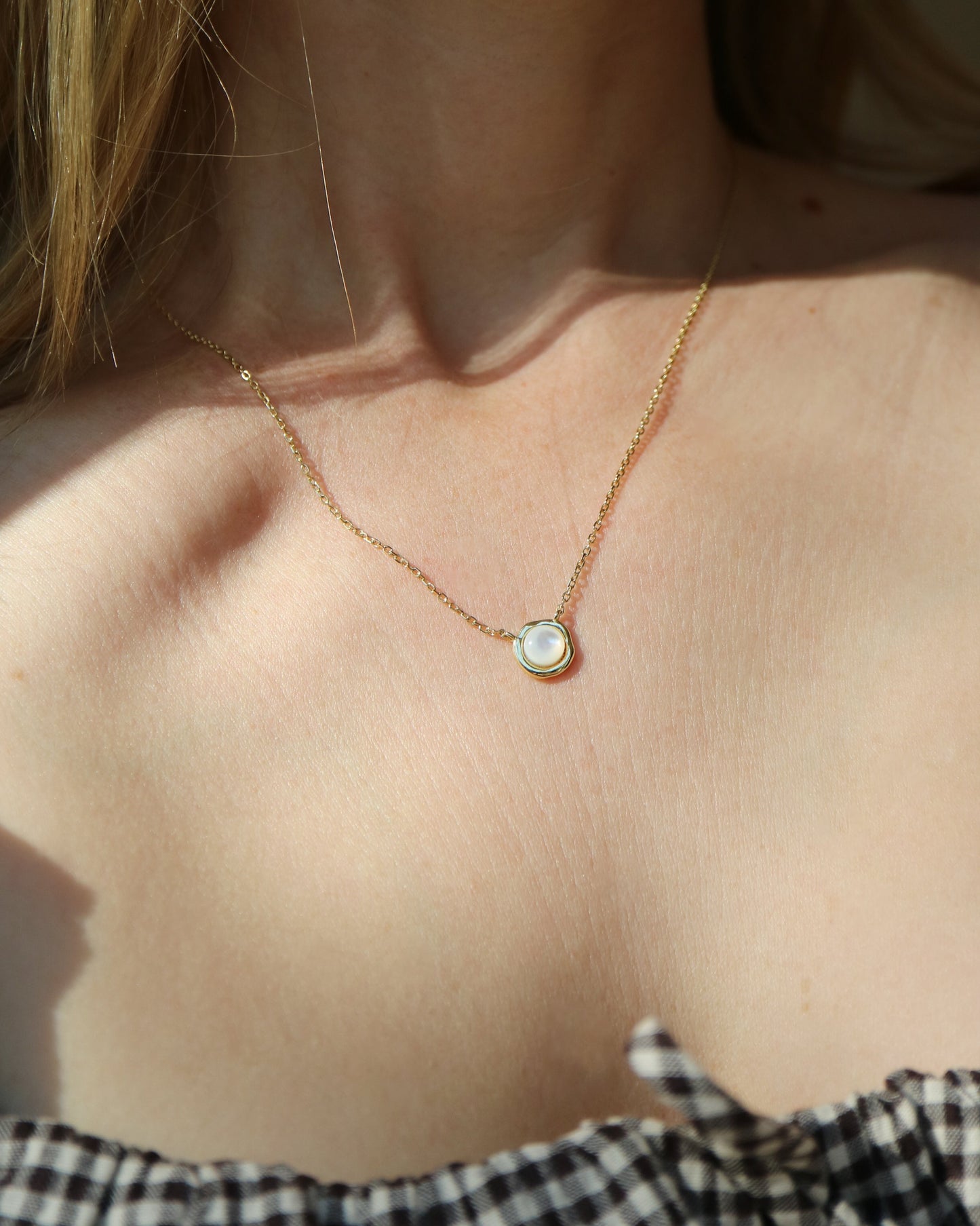 Necklace with a pendant worn by a person, with a blurred background