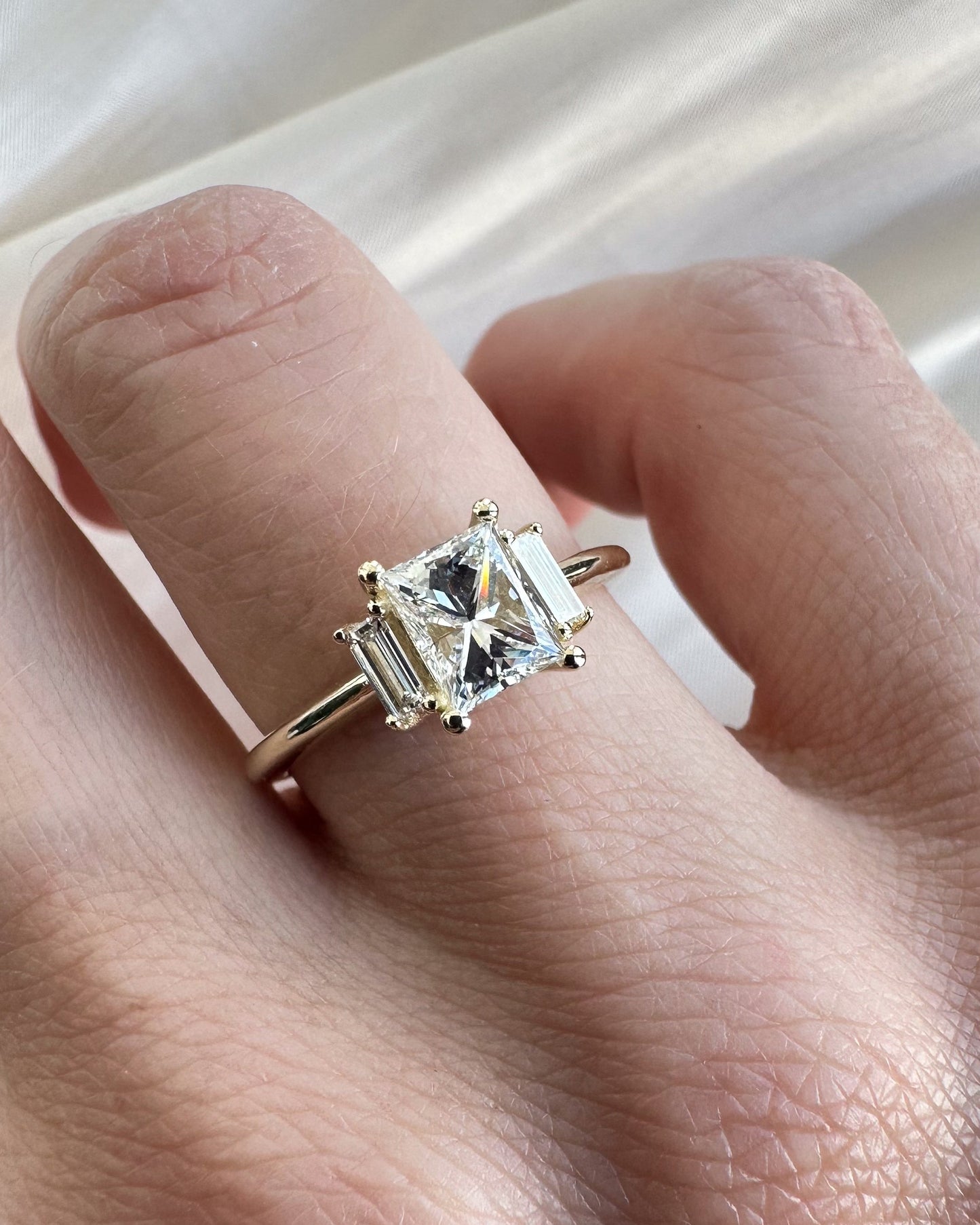 Gold ring with a diamond on a hand against a white background