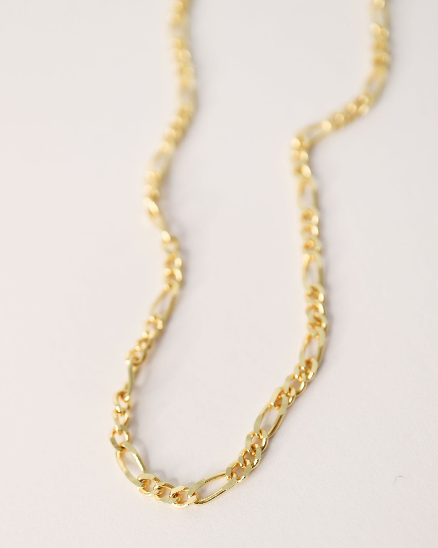 Gold chain necklace on a light gray background
