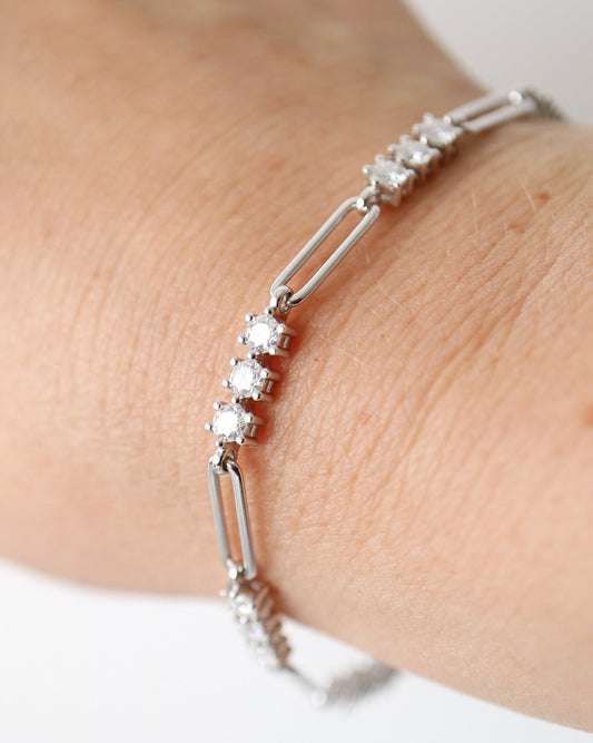 A silver-toned link bracelet with clear round-cut stones, shown worn on a person's wrist against a plain light background.