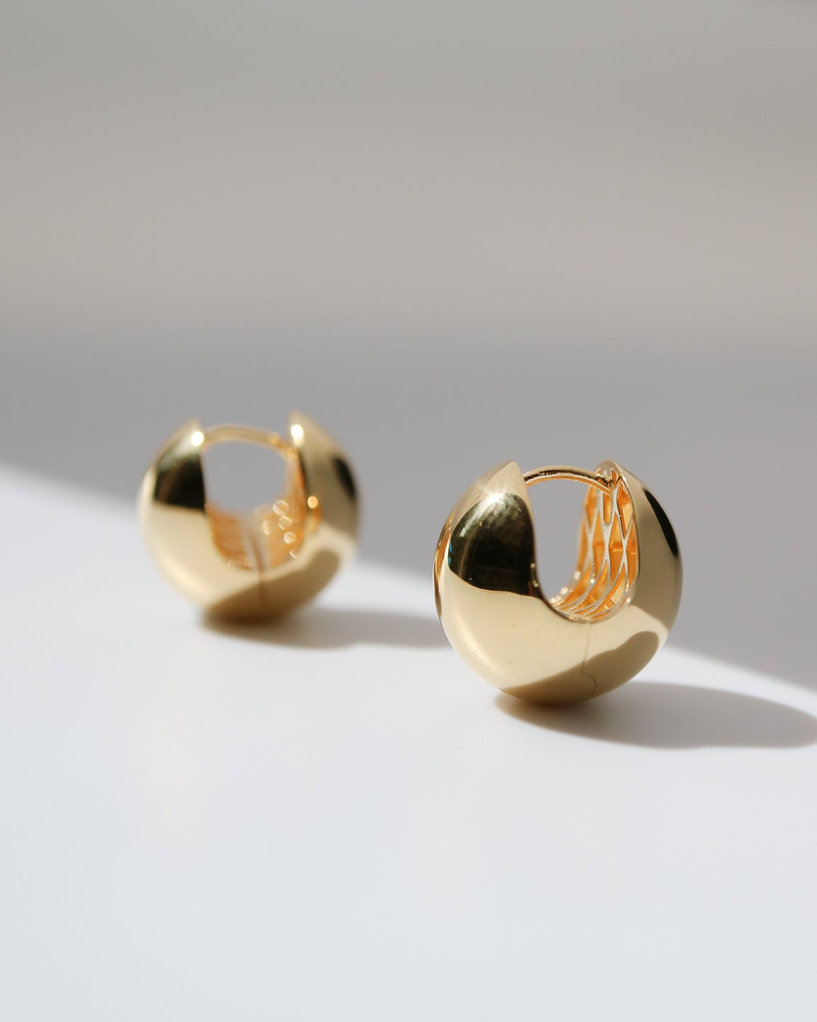 Pair of gold hoop earrings on a light gray background