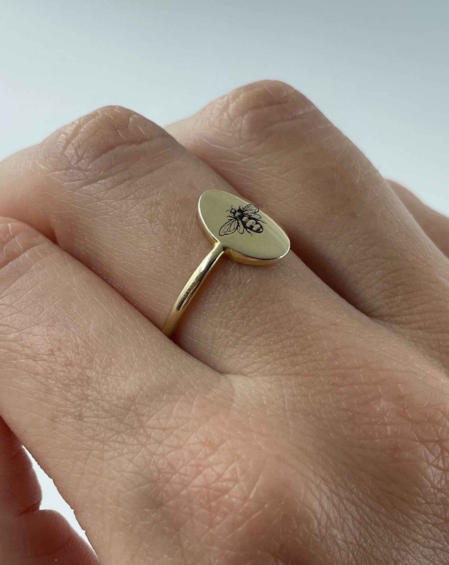 9ct gold oval ring with bee engraving, shown on hand