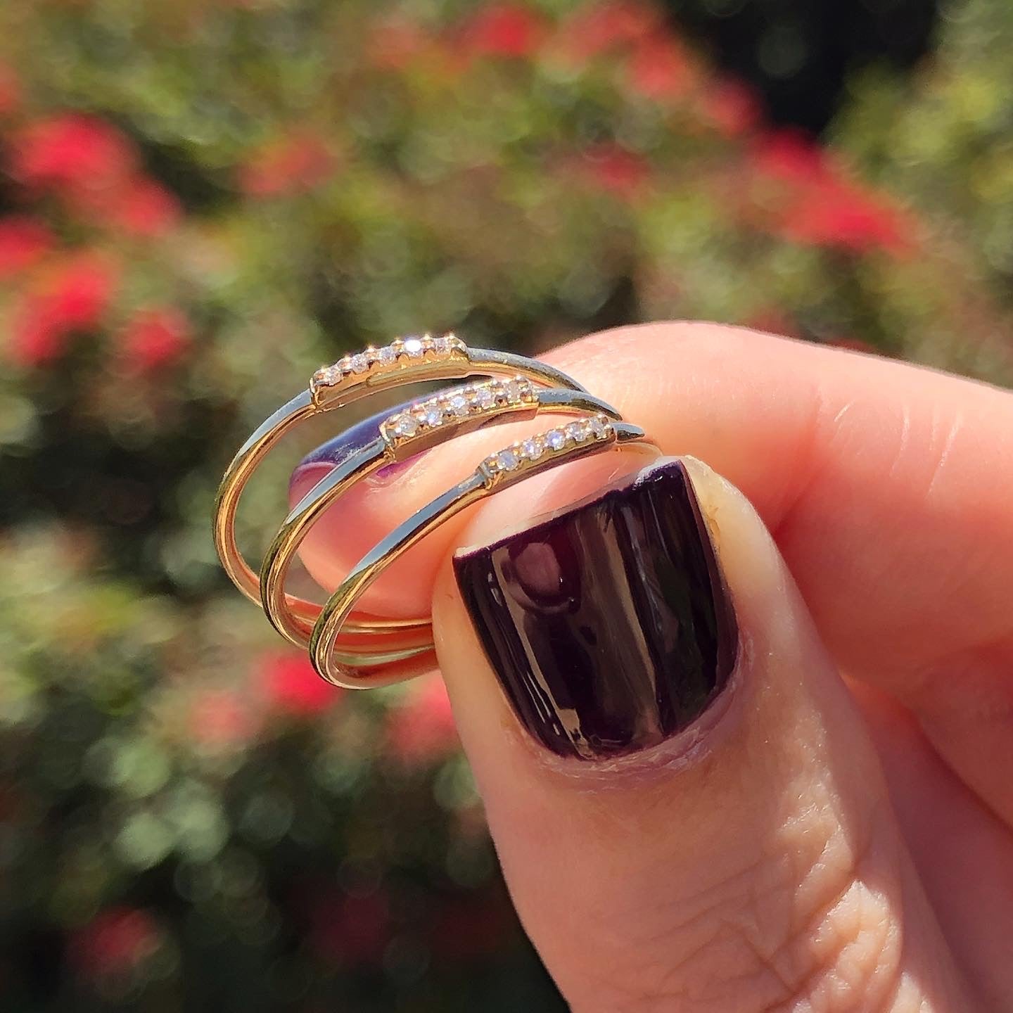 Fingers holding three gold and diamond stacking rings