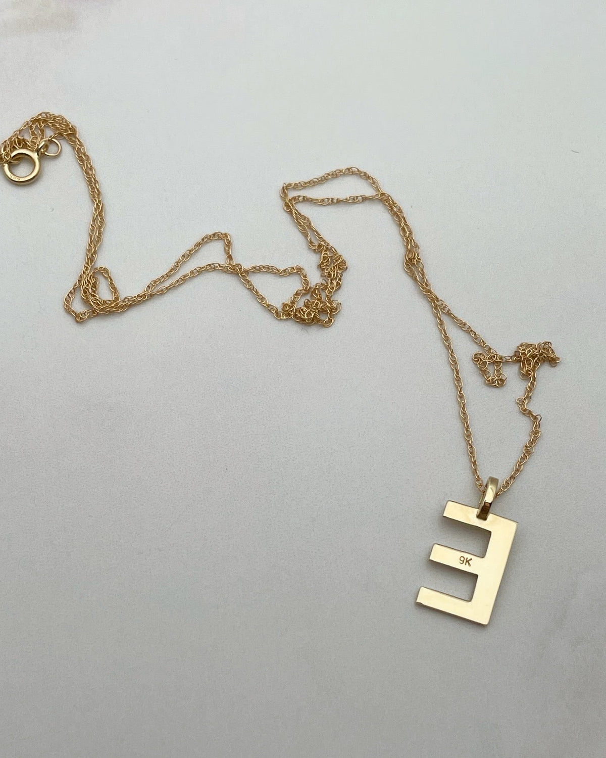 Solid 9kt gold initial pendant on white