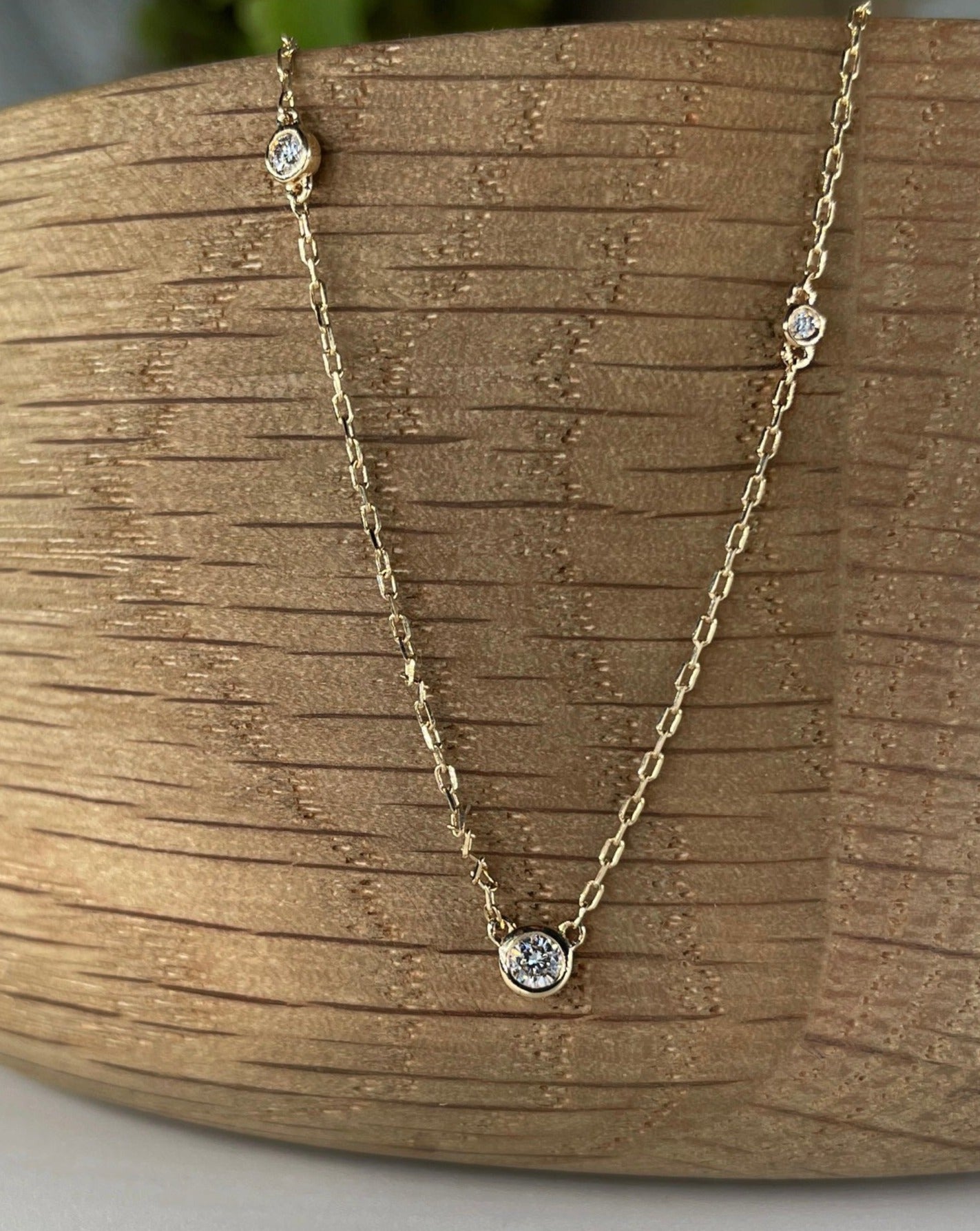 Close up of La Kaiser Eternal Diamond Love Pendant draped over wooden bowl