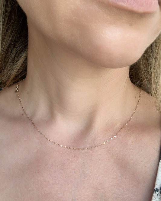 Close-up of a person wearing a delicate necklace with a blurred background