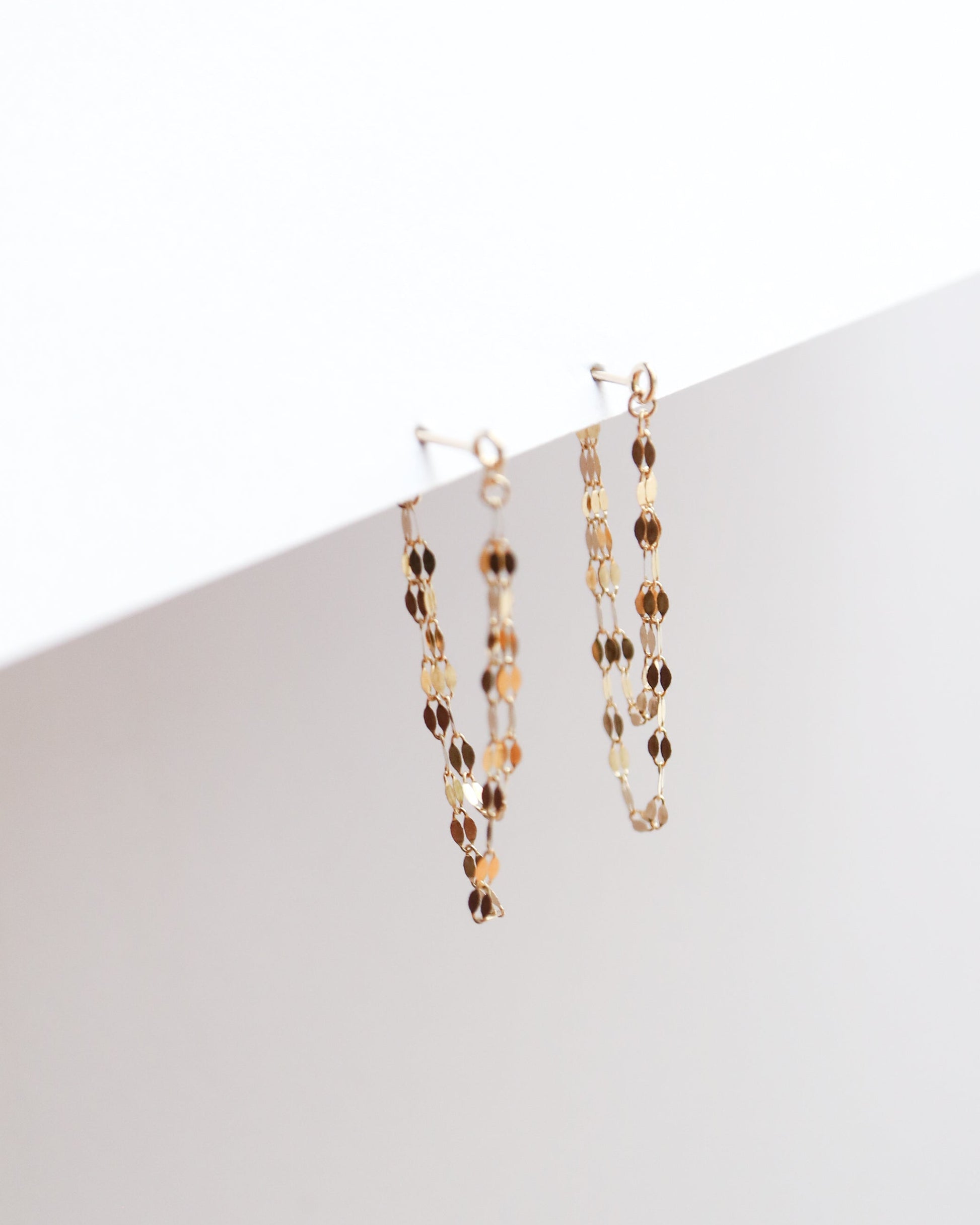 Two gold necklaces on a white surface