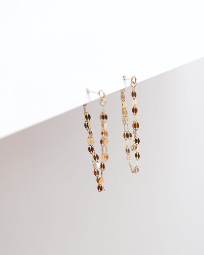 Two gold necklaces on a white surface