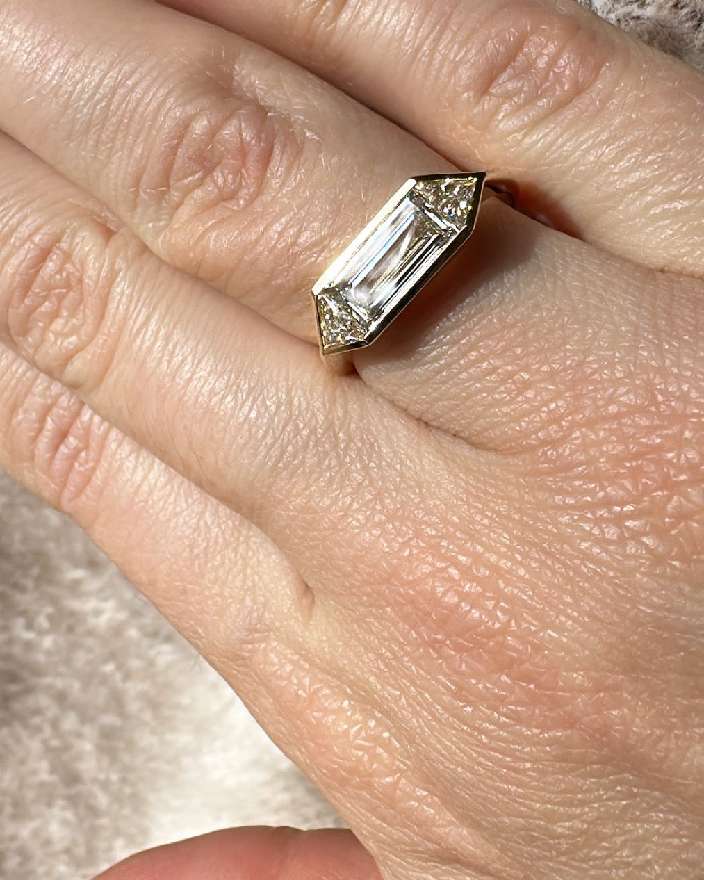 Hand wearing a diamond ring with a textured background