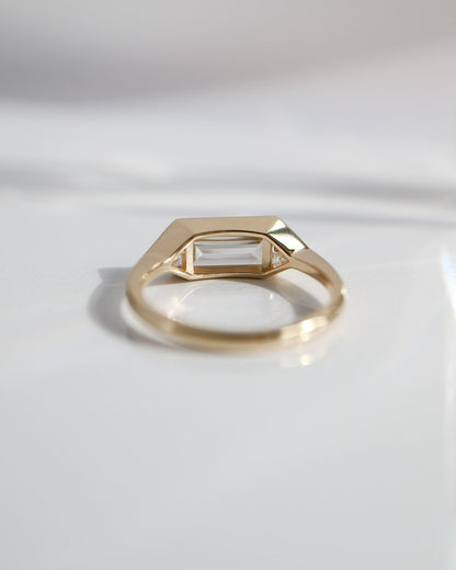 Gold ring with a rectangular gemstone on a light gray background