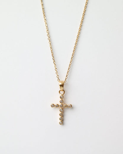 Gold cross necklace on a white background