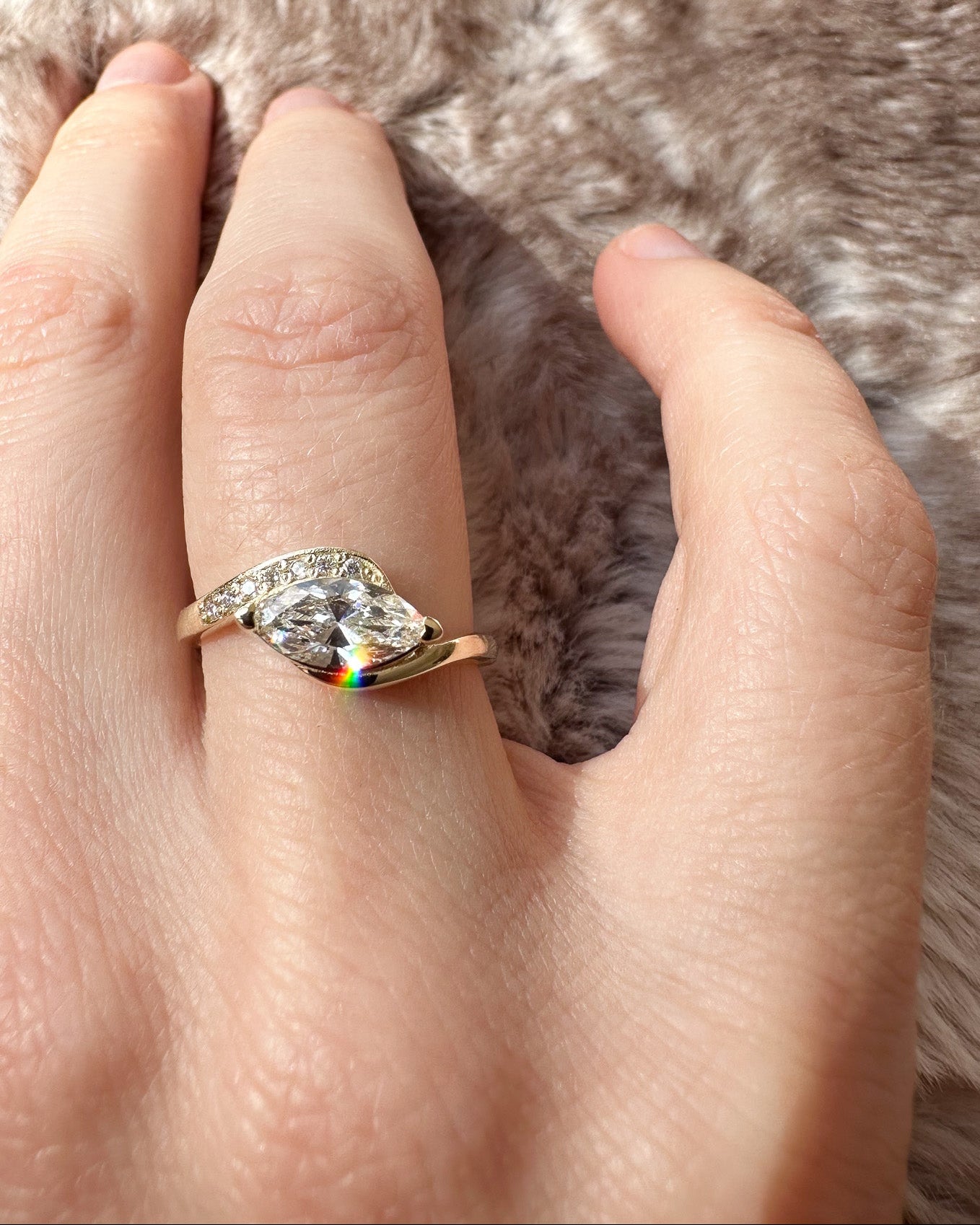 Hand wearing a ring with a large diamond on a fur background