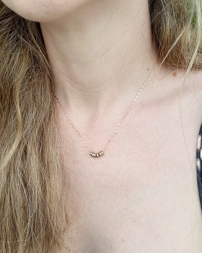 Close-up of a necklace with a small pendant on a person's neck.
