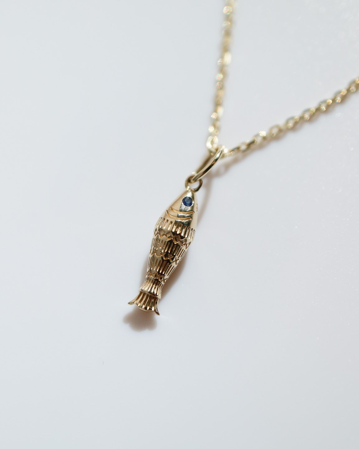 Gold necklace with a unique pendant on a light gray background