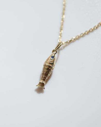 Gold necklace with a unique pendant on a light gray background