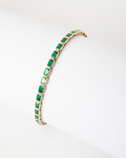 Gold bracelet with green gemstones on a white background
