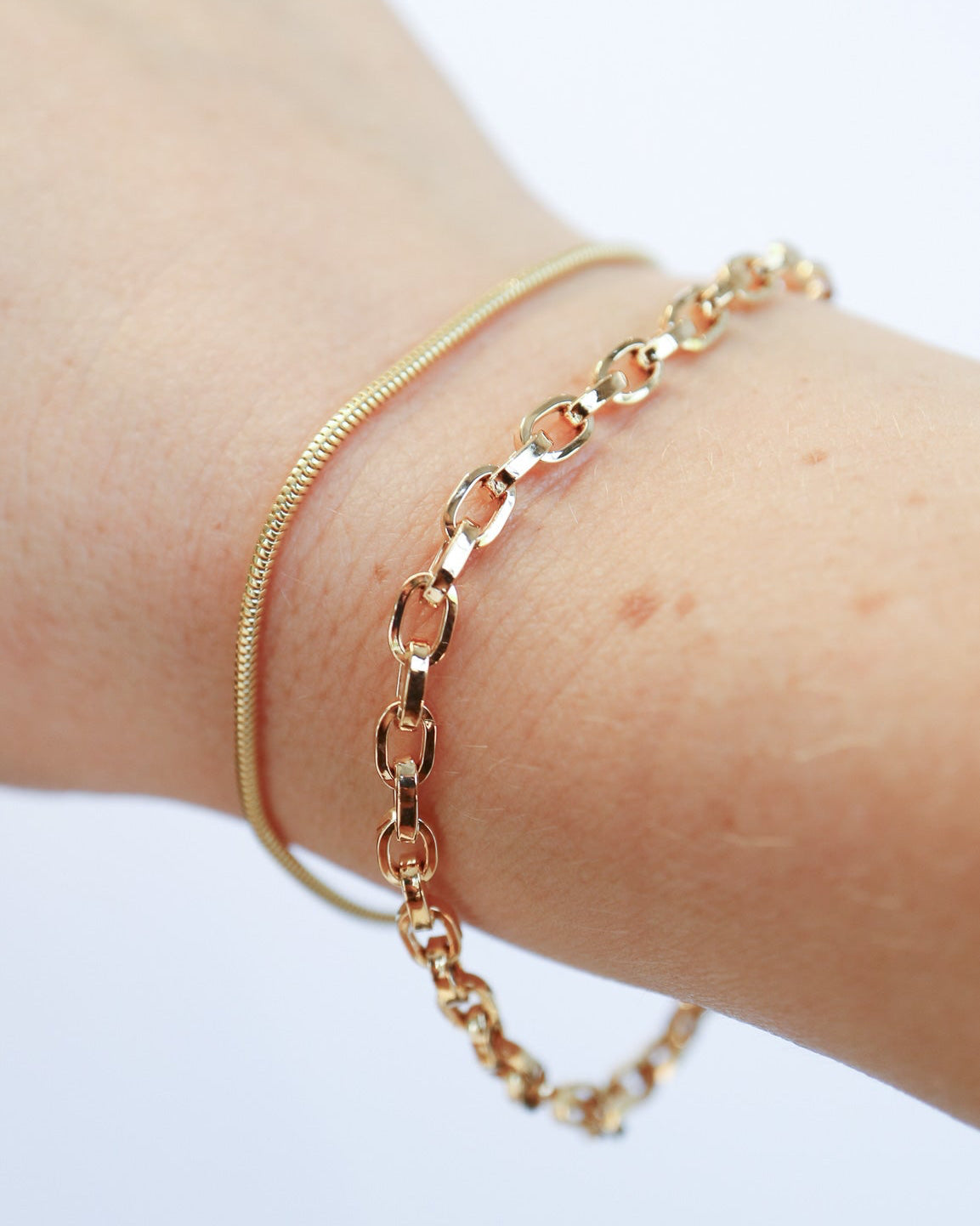 9ct gold Snake and Link Bracelets stacked on female wrist