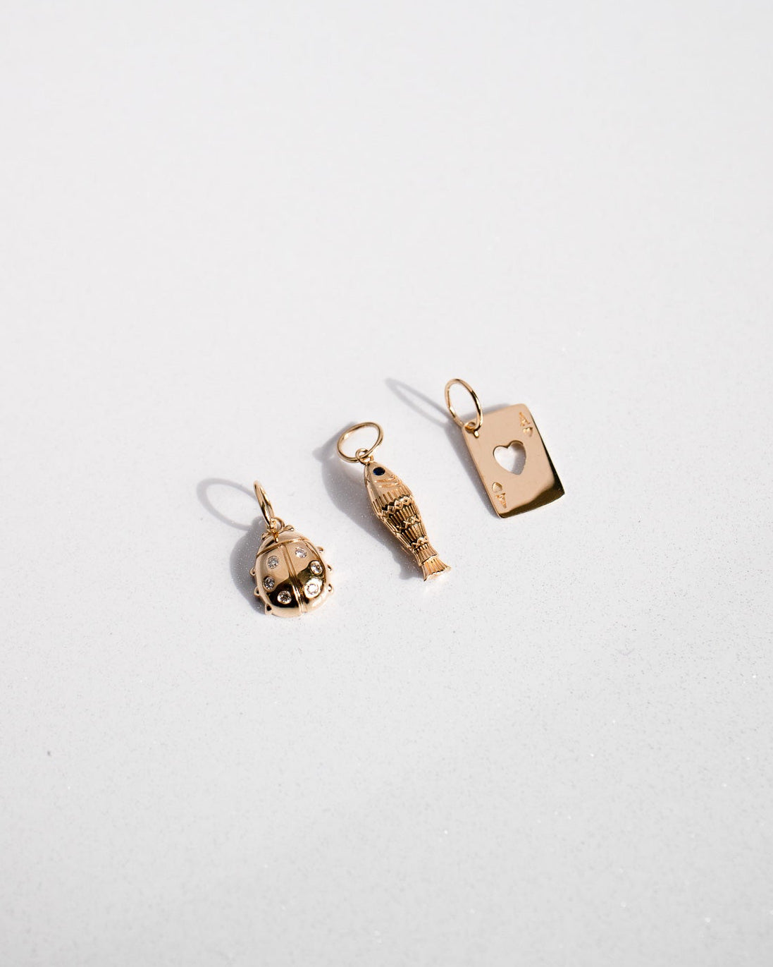 Three gold charm pendants on a white background