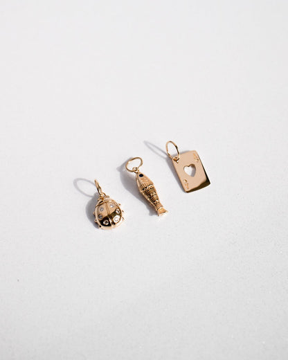 Three gold charm pendants on a white background