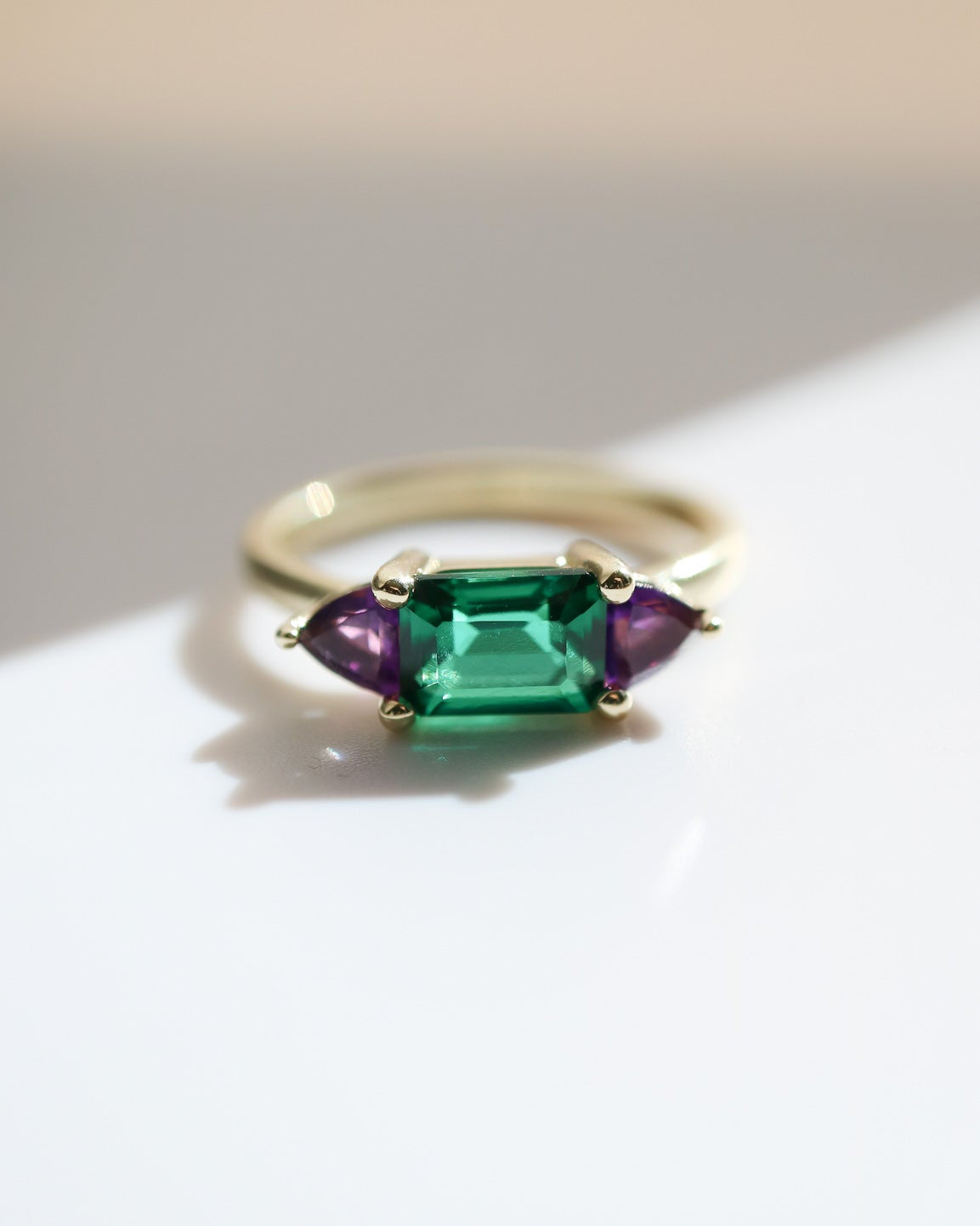 Ring with emerald and amethyst stones on a light background