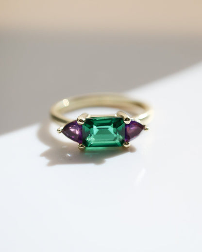 Ring with emerald and amethyst stones on a light background