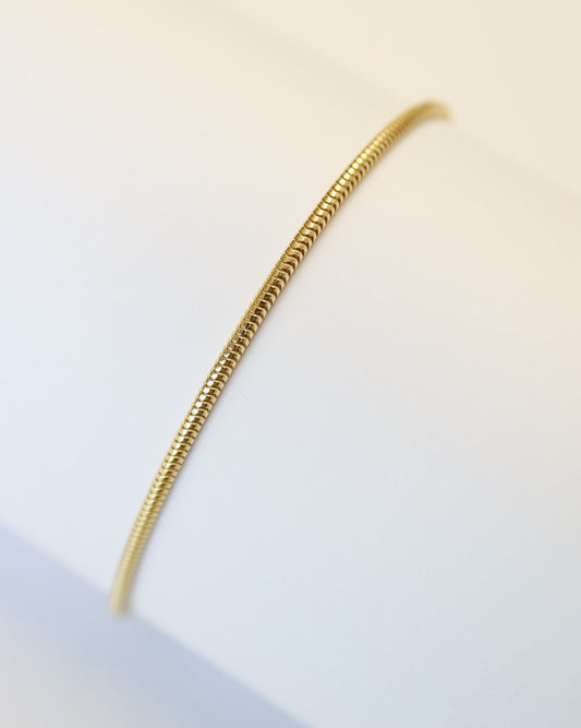 9kt gold snake chain bracelet on white tube background