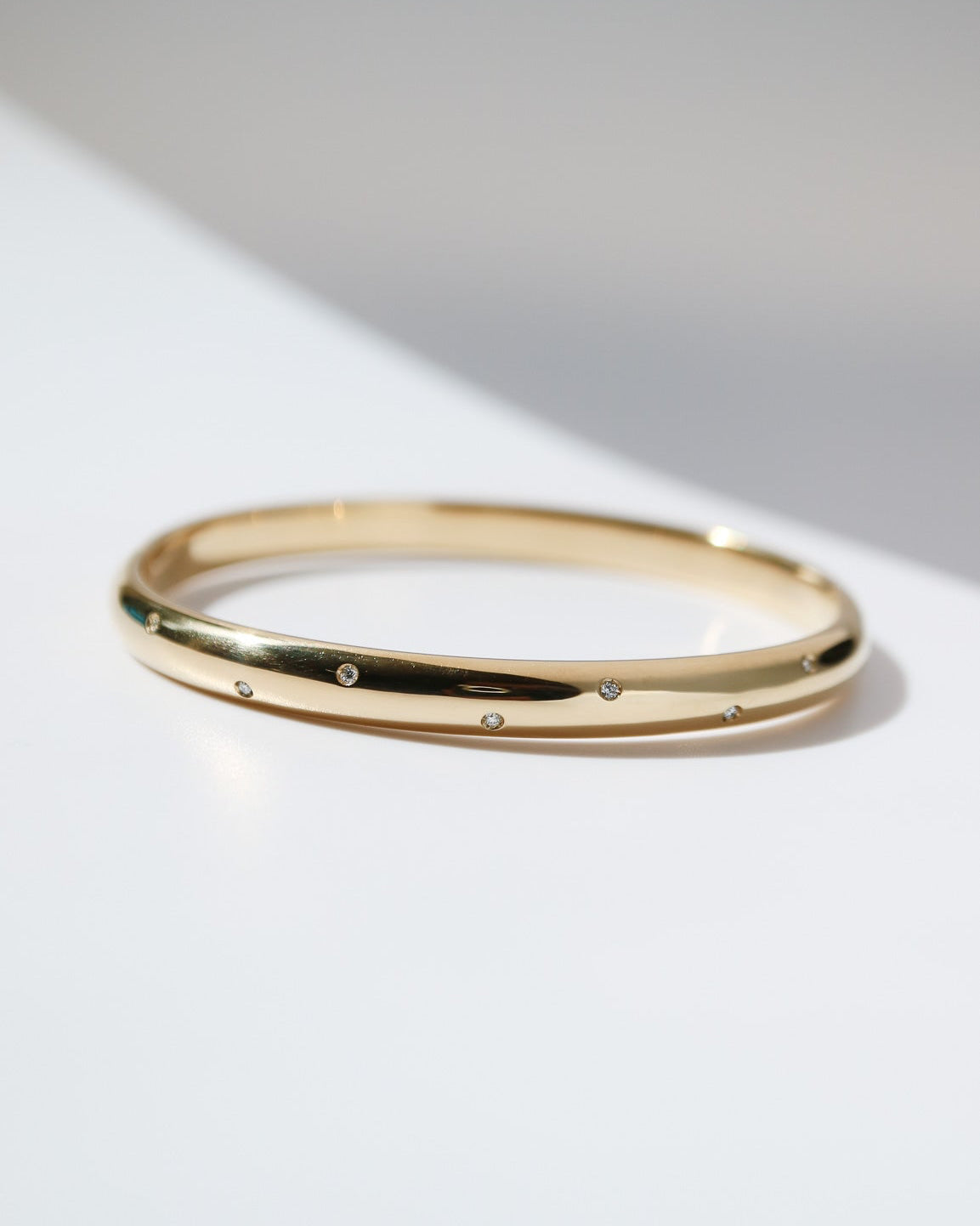 9kt yellow gold bangle with scattered lab-grown diamonds and a polished finish on a white background.