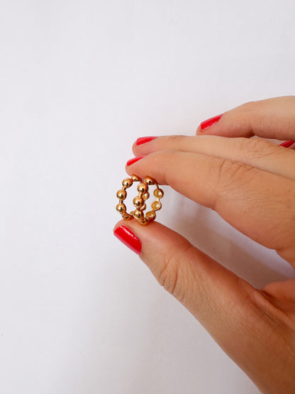 Hand holding 9k gold beaded earrings against a white background
